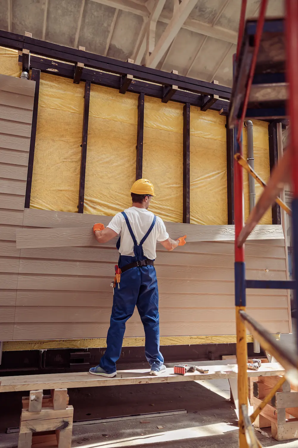 Lee-Built Construction worker installing siding on a remodel of an office building